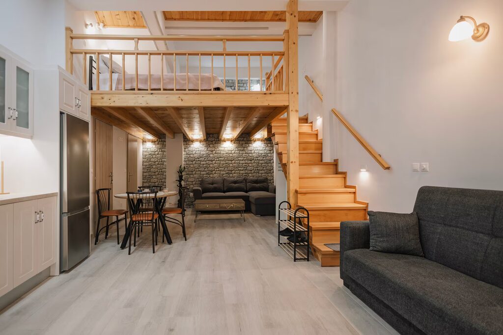 The open living room seen from the doorway, with the wooden loft above and pine beams across the ceiling.